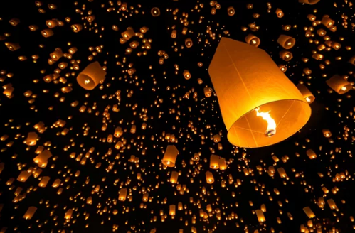 Orange sky lanterns glowing against a dark night sky