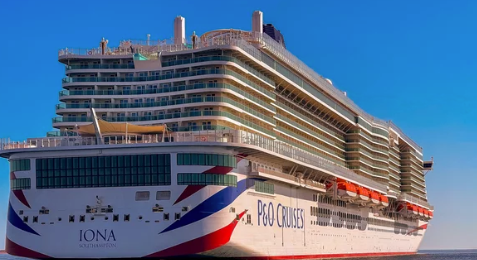 Large white cruise ship “IONA” with P&O Cruises branding sailing on calm blue water under a clear sky
