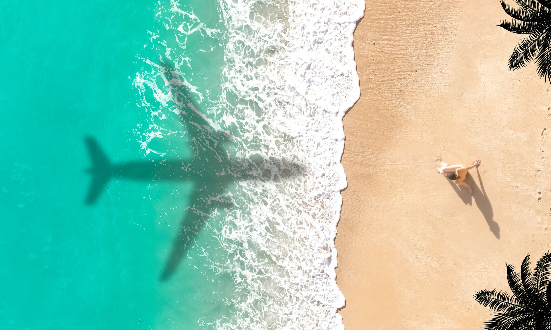 Aerial view of a beach with turquoise waves, an airplane shadow on the water, and a person walking on the sand