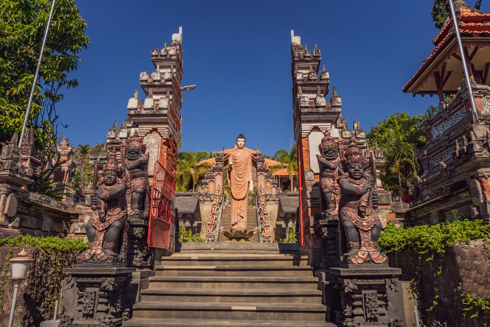 Stone temple stairs framed by ornate gates and statues under a clear blue sky
