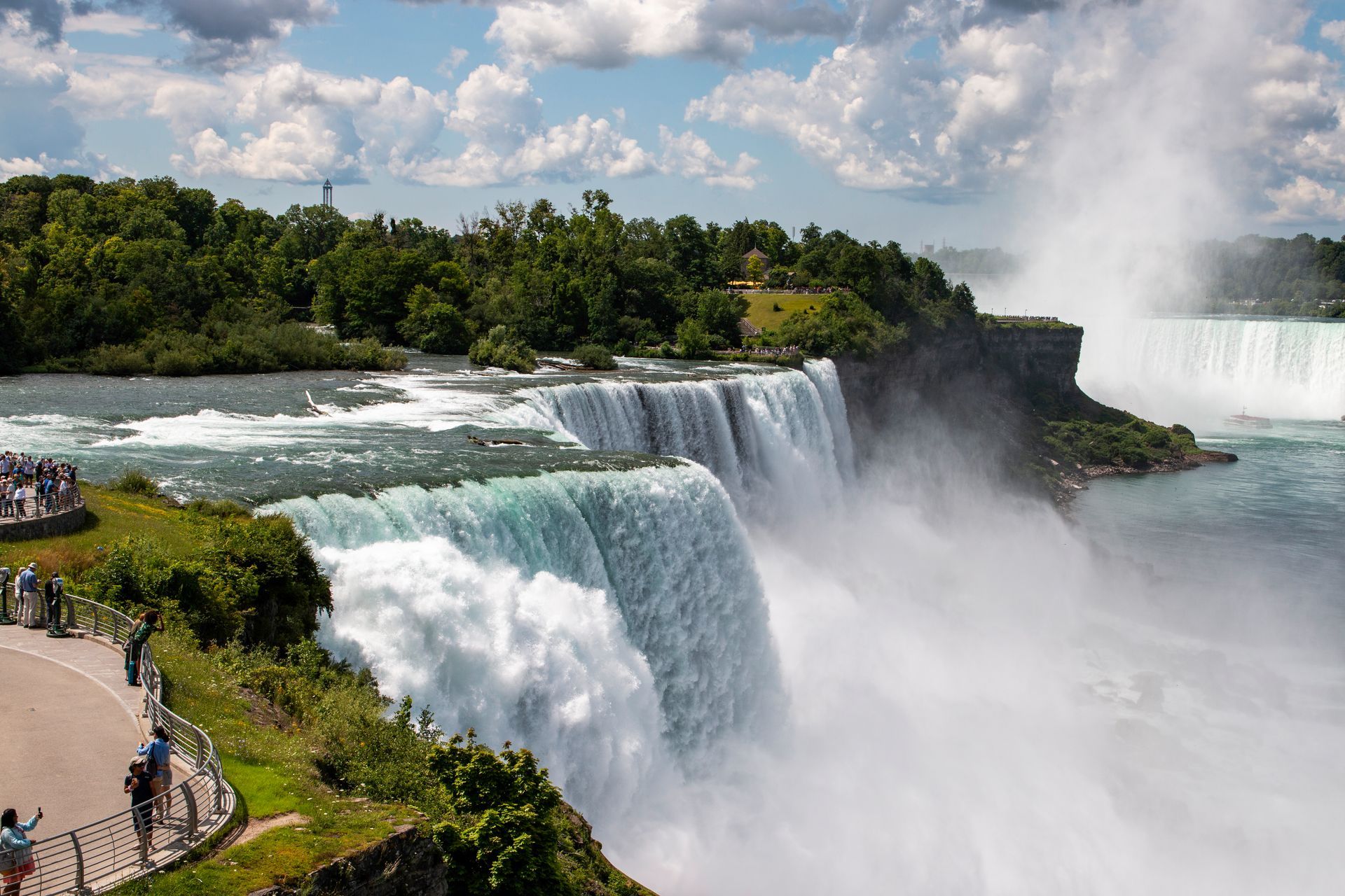 Niagara Falls with rushing water, mist, and visitors along the scenic overlook