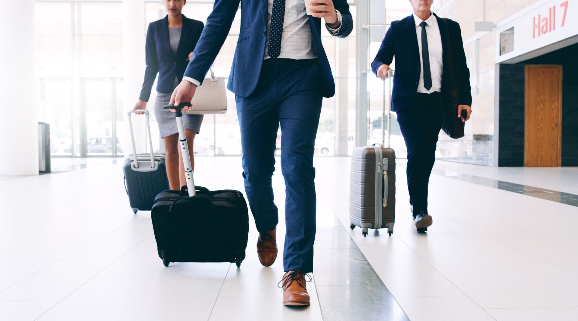 Business travelers walking through an airport terminal with rolling suitcases