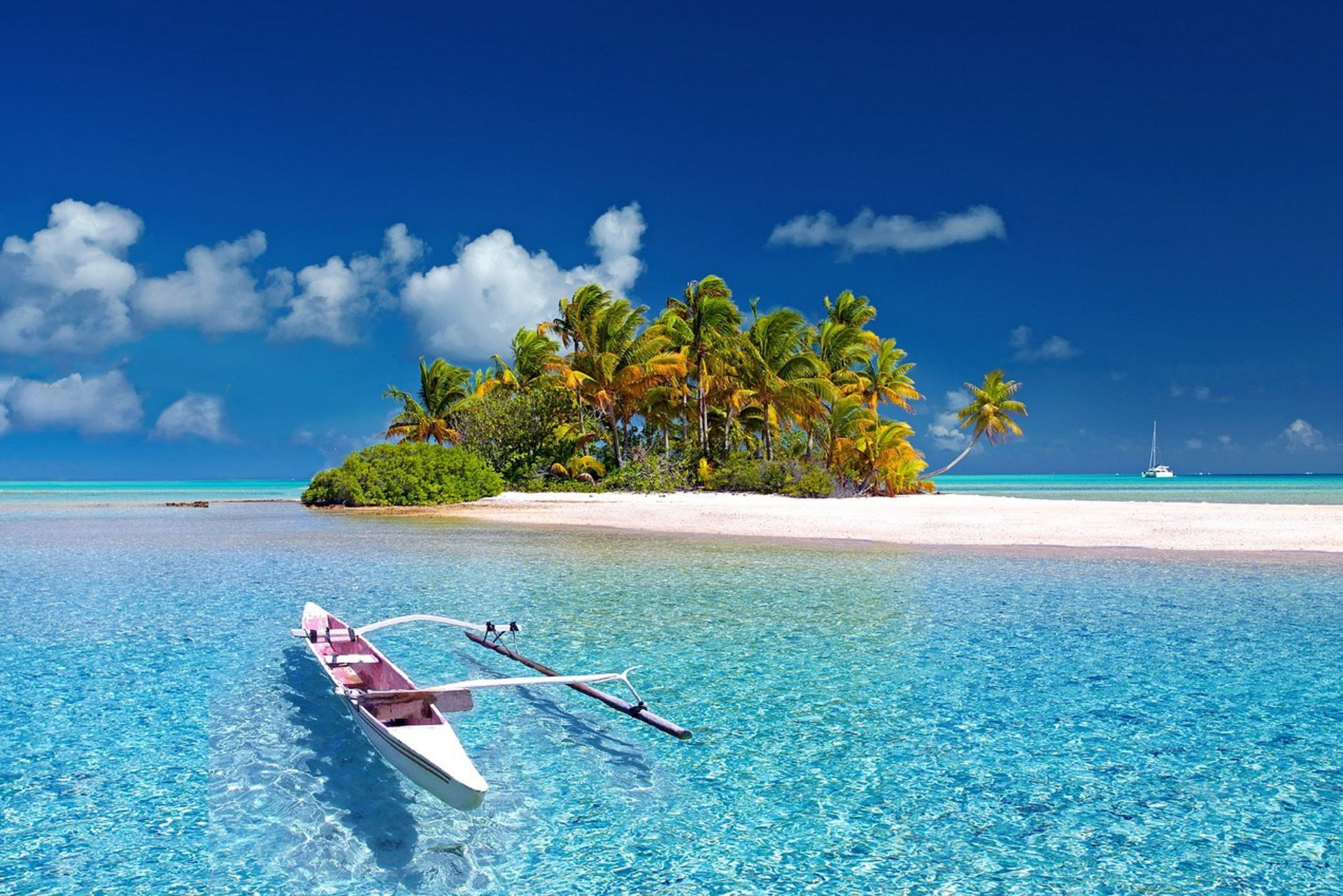 Small outrigger boat on turquoise water near a sandy tropical island under a bright blue sky