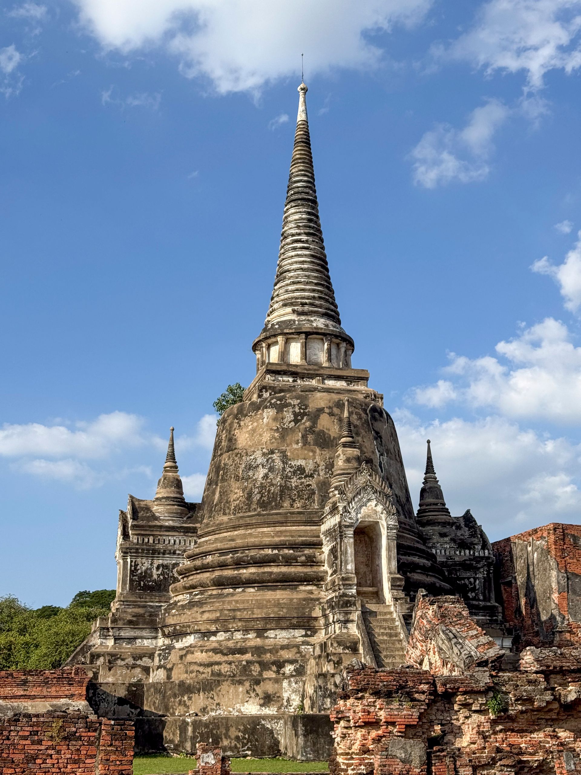 Ancient stone temple with tall spire under a blue sky with clouds