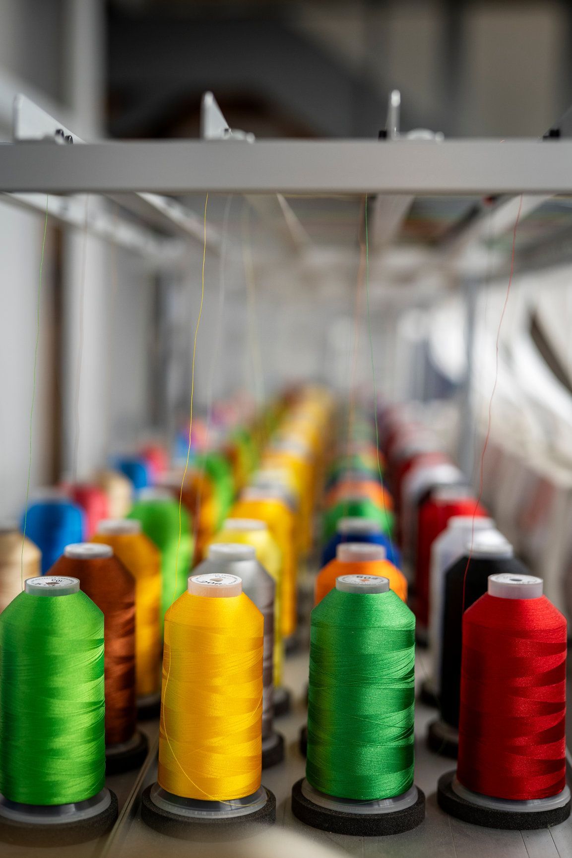 Colorful spools of thread lined up on a rack, likely for embroidery or sewing.