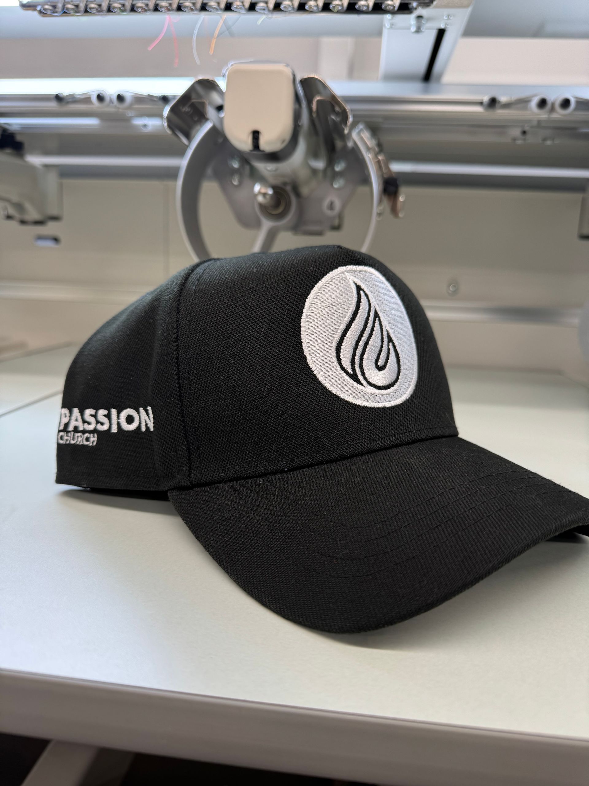 Black baseball cap with embroidered logo of white flame on white circle. 