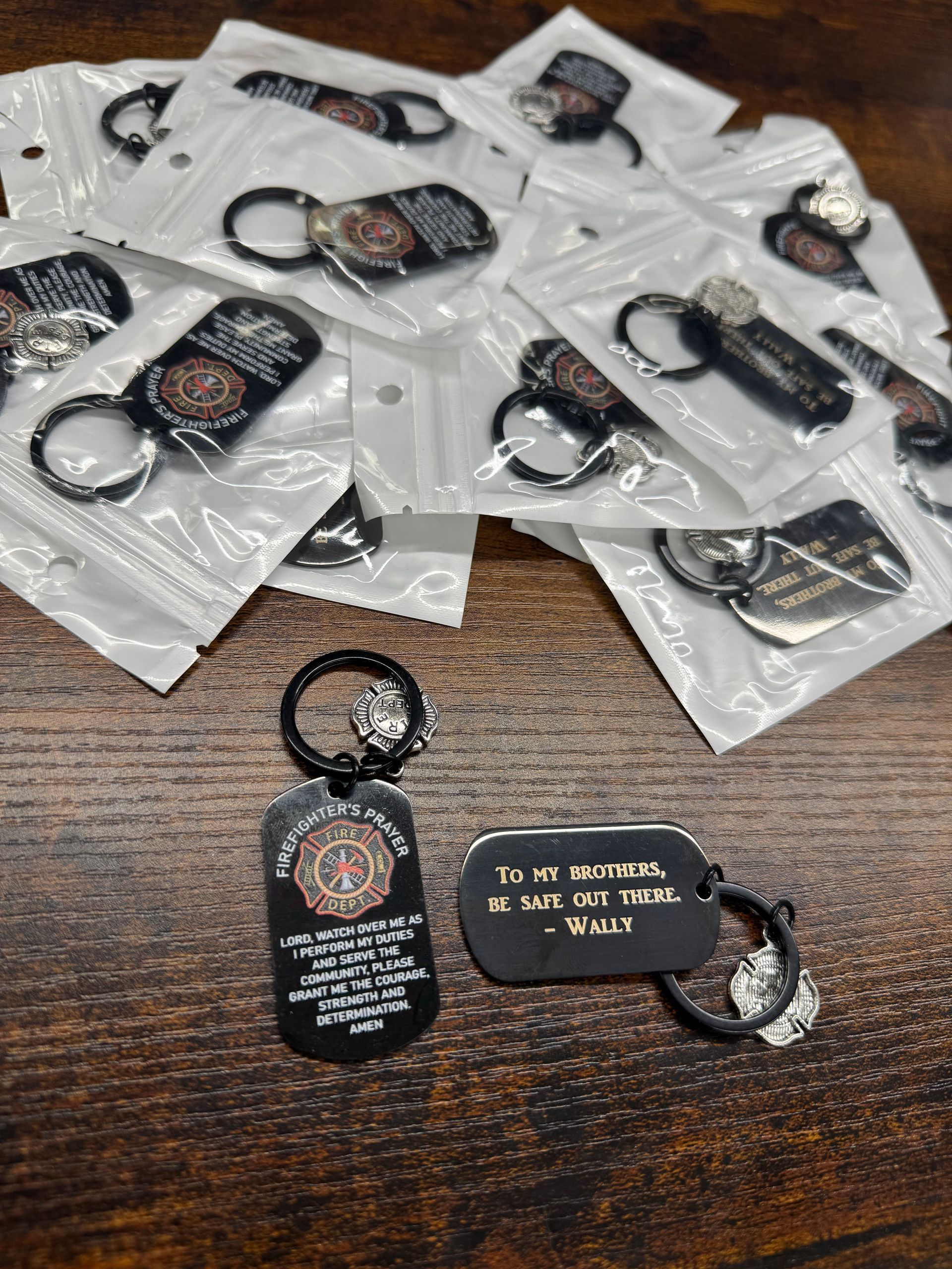 Keychains for firefighters, black metal tags, packaged in plastic. One has the message 