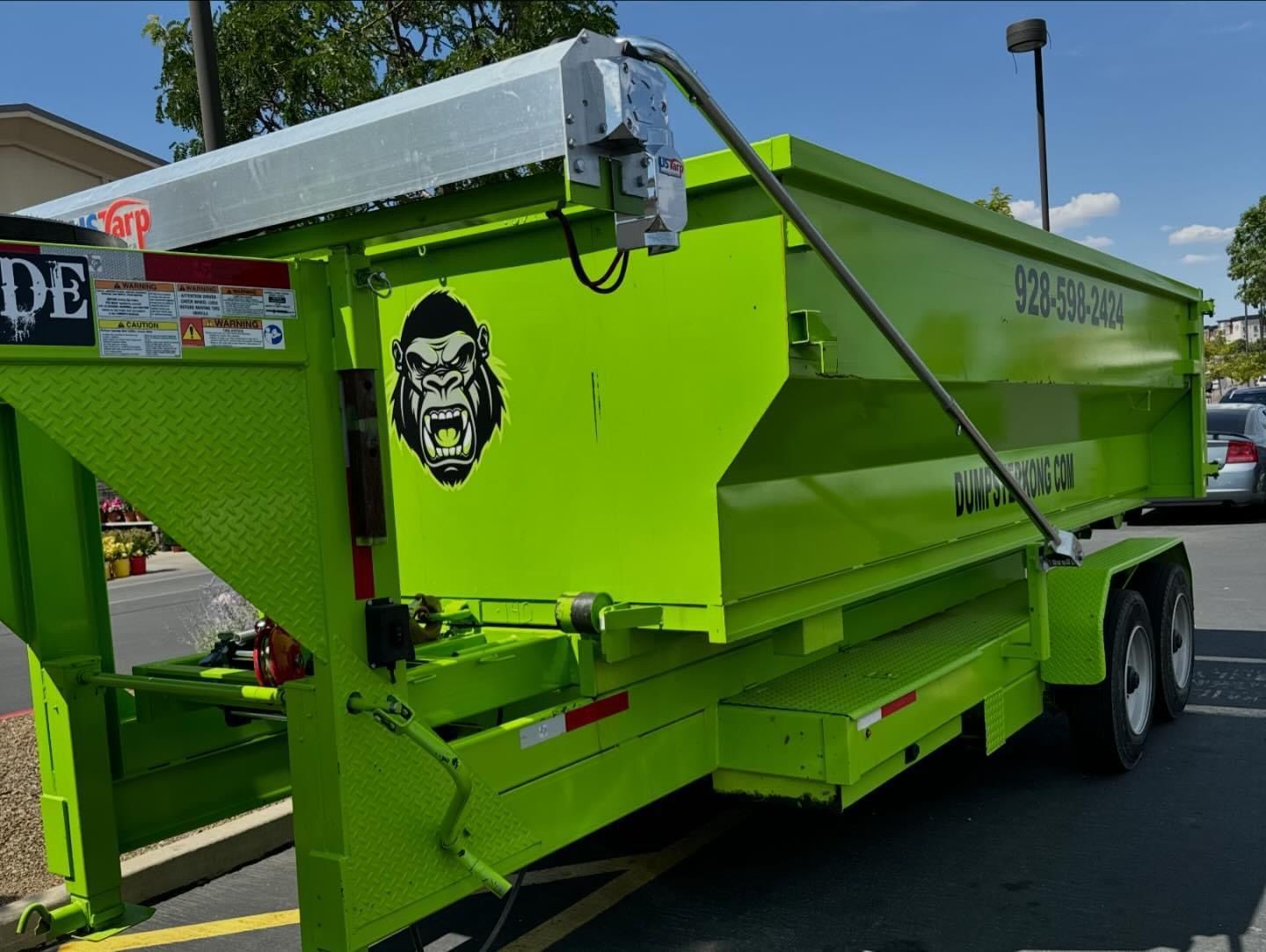 Bright green Gorilla Dumpster trailer with gorilla logo, outdoors, sunny day.