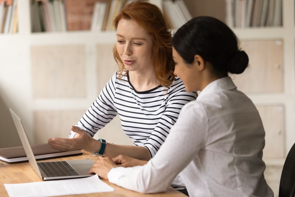 Two Women Are Sitting at A Table Looking at A Laptop Computer — Psych Solutions NT in Leanyer, NT