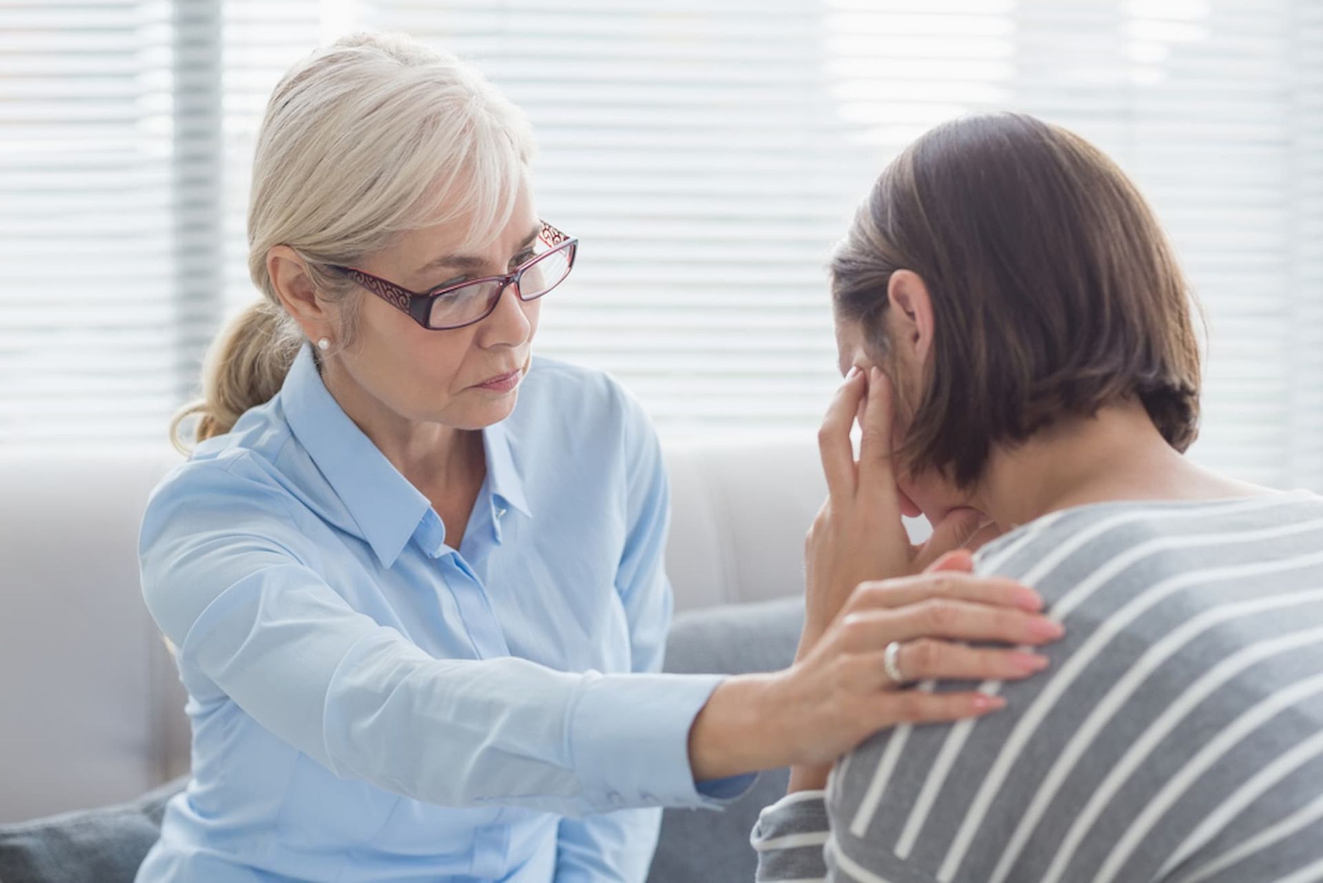 A Woman Is Comforting Another Woman Who Is Sitting on A Couch — Psych Solutions NT in Alice Spring, NT