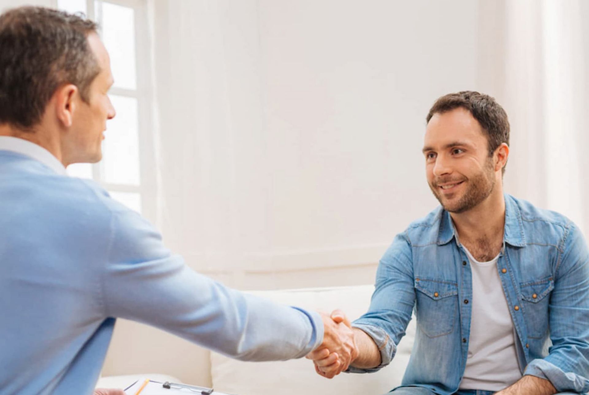 A Man Is Shaking Hands with Another Man While Sitting on A Couch — Psych Solutions NT in Leanyer, NT
