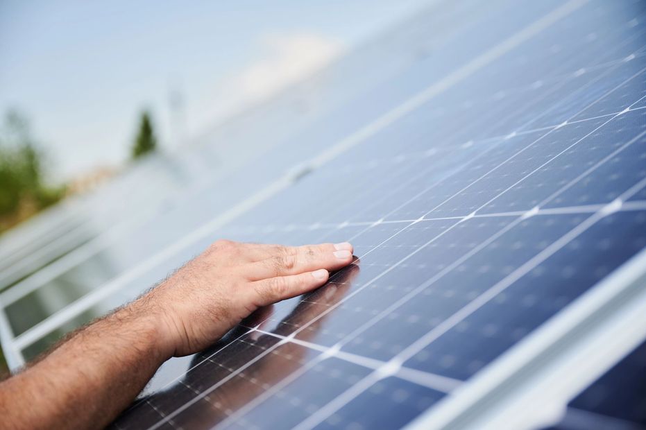 Una mano che tocca un pannello solare in piena luce del sole