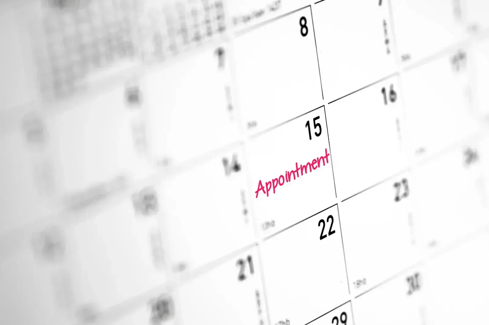 Close-up of a white calendar page with dates marked, showing “Appointment” in red on the 15th.