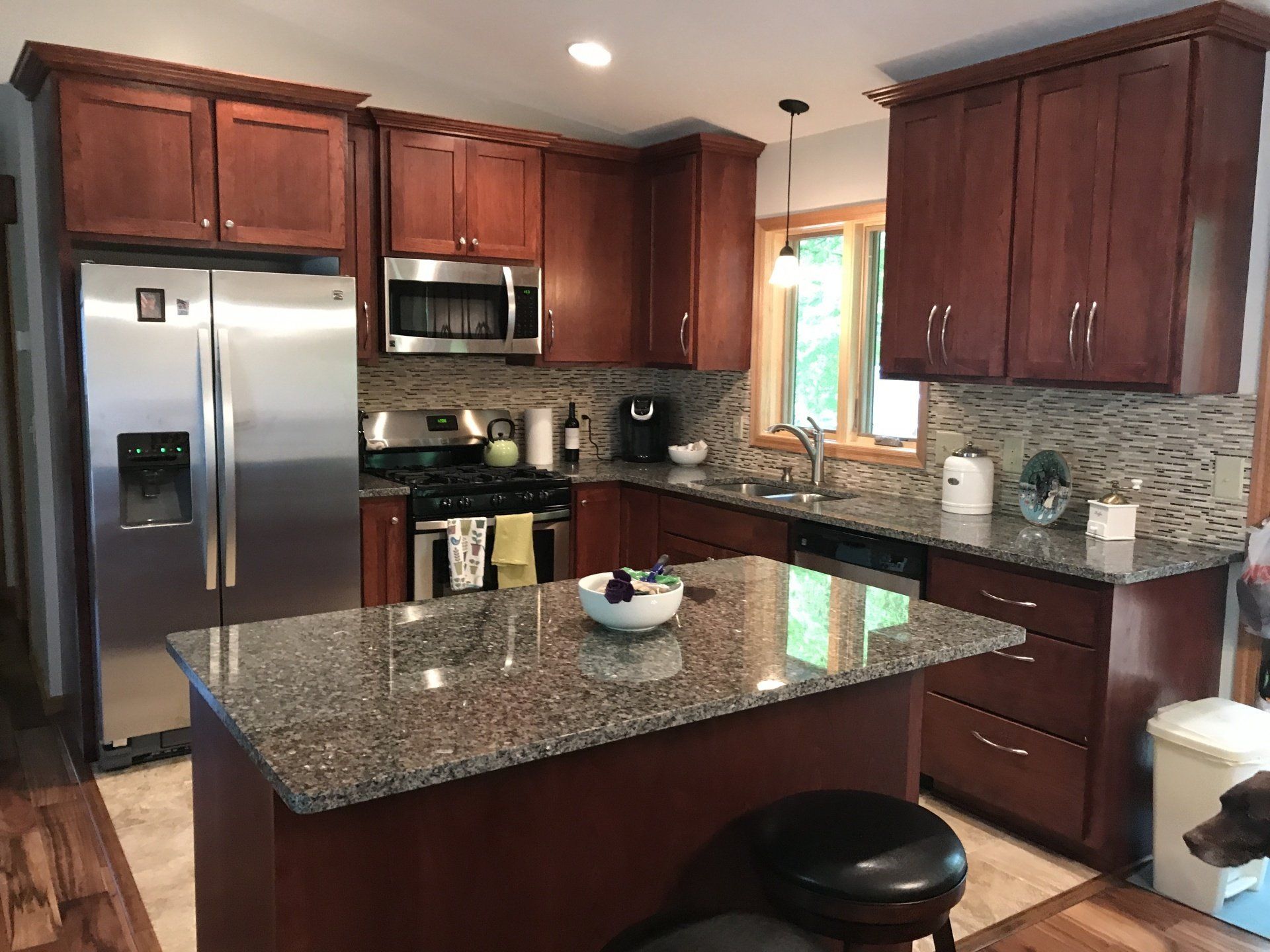Kitchen with dark wood cabinets, stainless steel appliances, granite countertops, and an island.