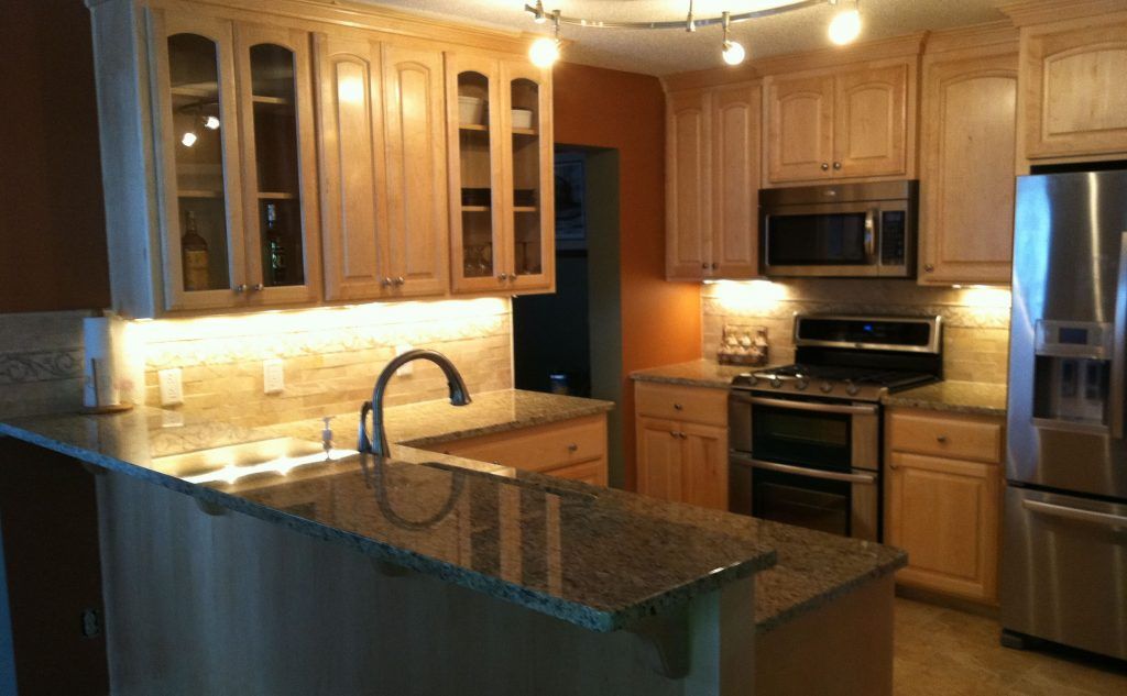 Beige kitchen with granite countertops, stainless steel appliances, and wooden cabinets.