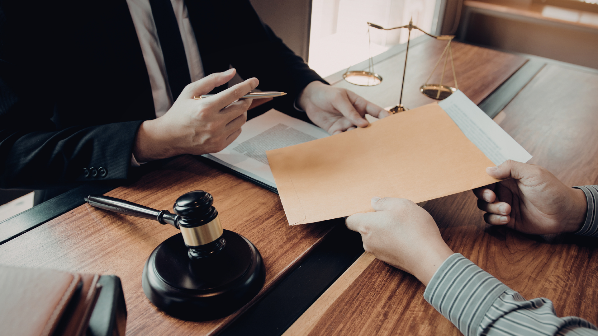 Two people review documents at a wooden table with a gavel in a meeting room.