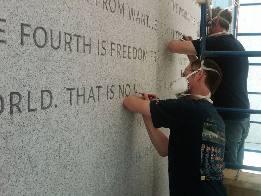 An image of Nick Benson and Paul Russo applying a tint to the lettering at Four Freedoms Park in New York, which used the same font planned for Peace Corps Park.