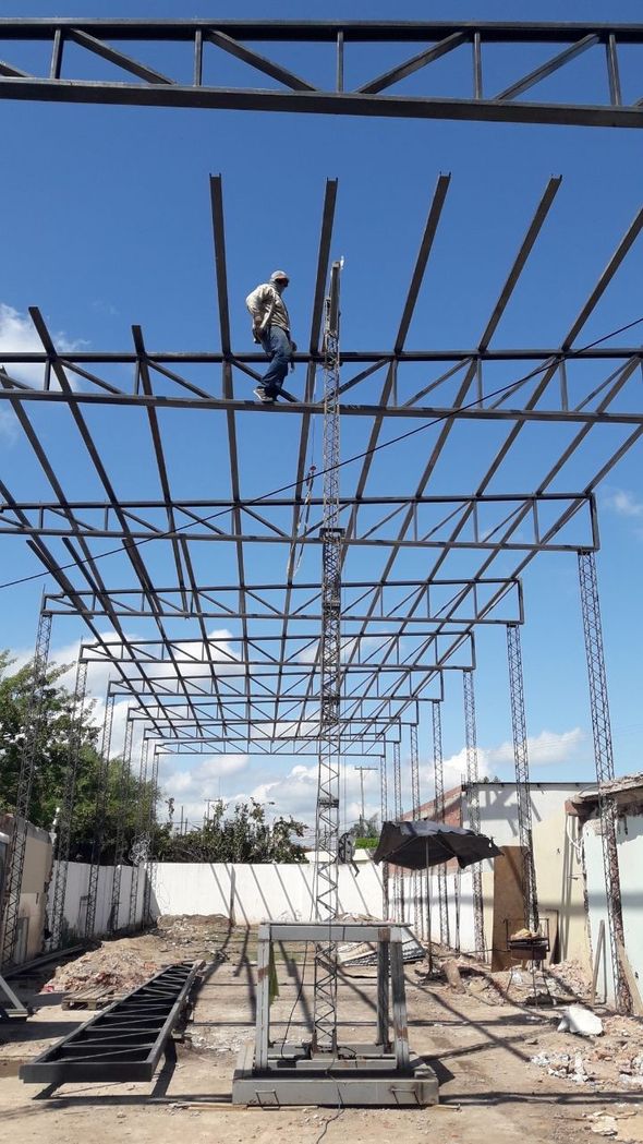Obrero de la construcción en una estructura de acero, en fase de montaje en un patio al aire libre.