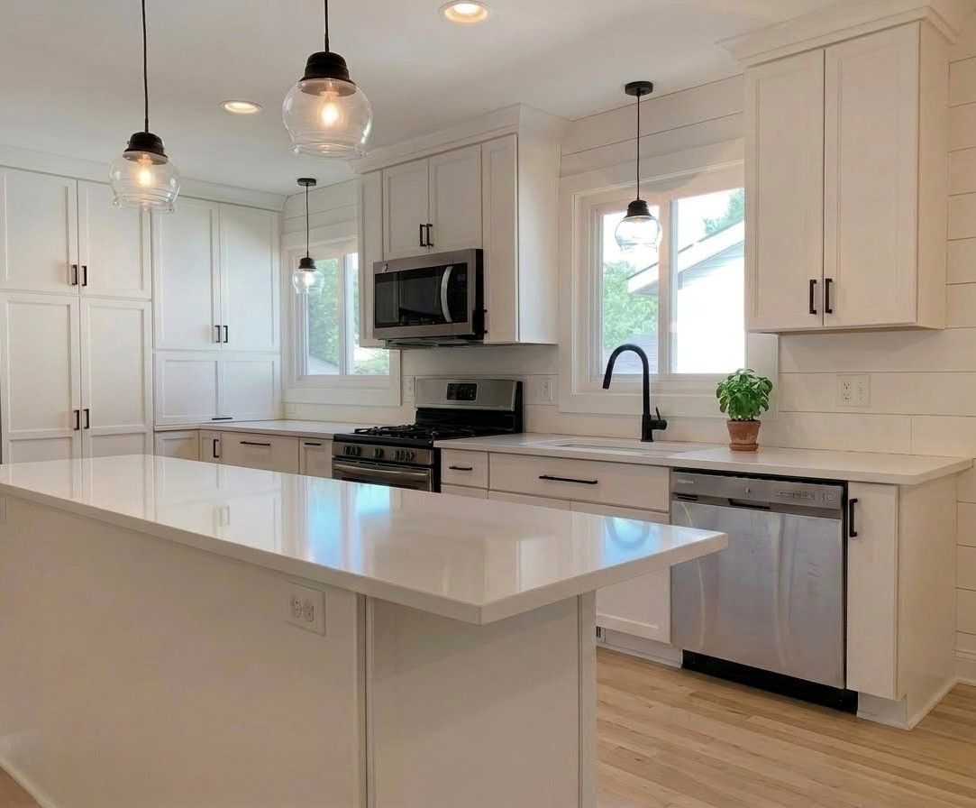 Modern kitchen with white island, black stools, wood floors, and a large black range hood