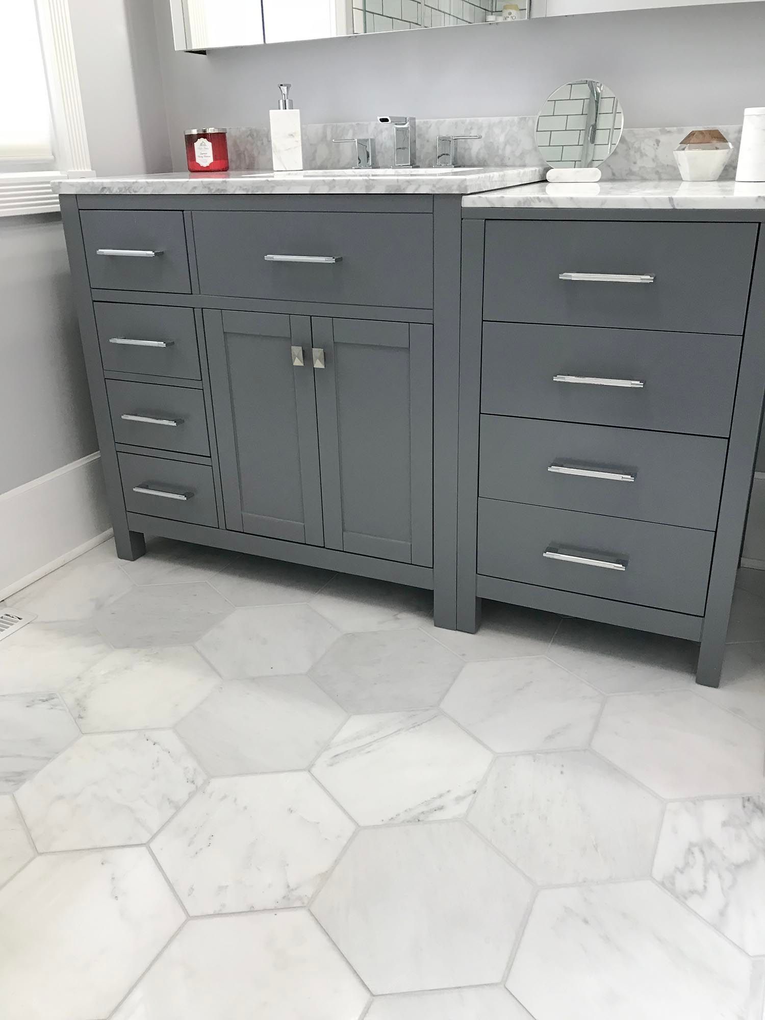 Gray bathroom vanity with drawers and cabinet under a white countertop and sink in a tiled room