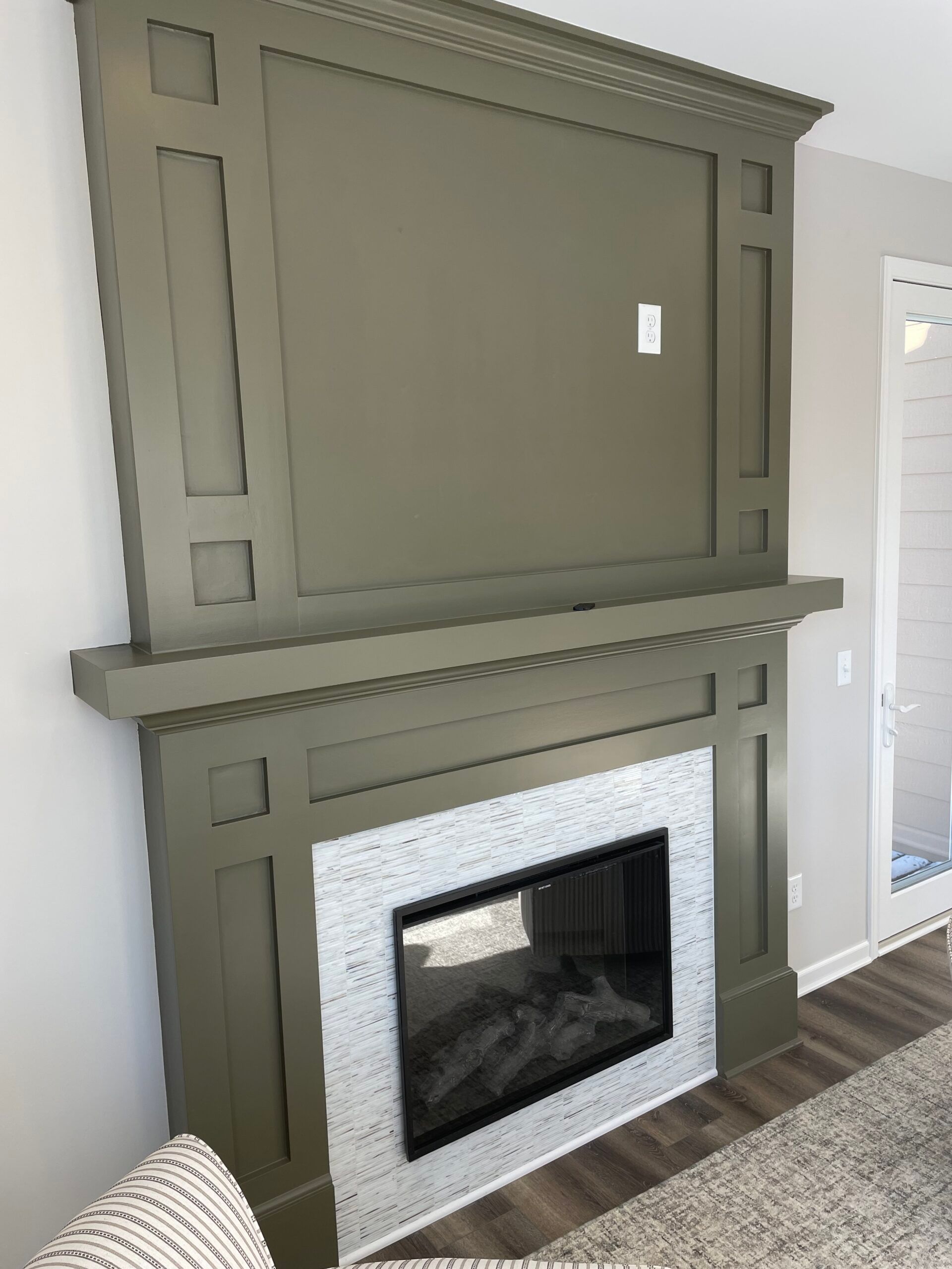 Olive green fireplace mantel with white tile surround in a living room