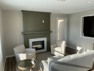 Bright living room with gray fireplace, striped armchairs, round table, and sectional sofa. Bright living room with gray fireplace, striped armchairs, round table, and sectional sofa.