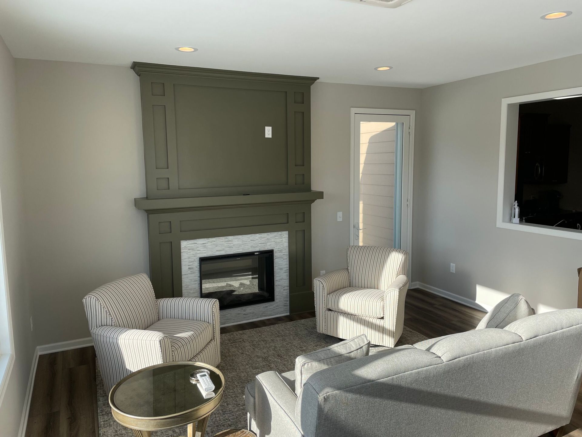 Living room with gray fireplace, two patterned chairs, sofa, and a round gold coffee table