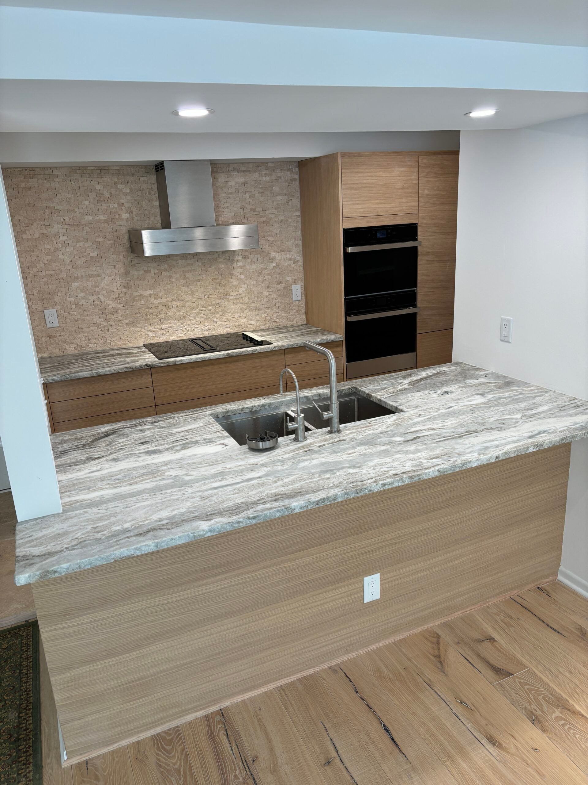 Modern kitchen with granite island, stainless range hood, and wood flooring