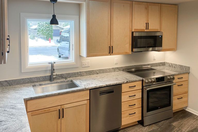 Kitchen under renovation with blue-covered cabinets, stone backsplash, and built-in oven.