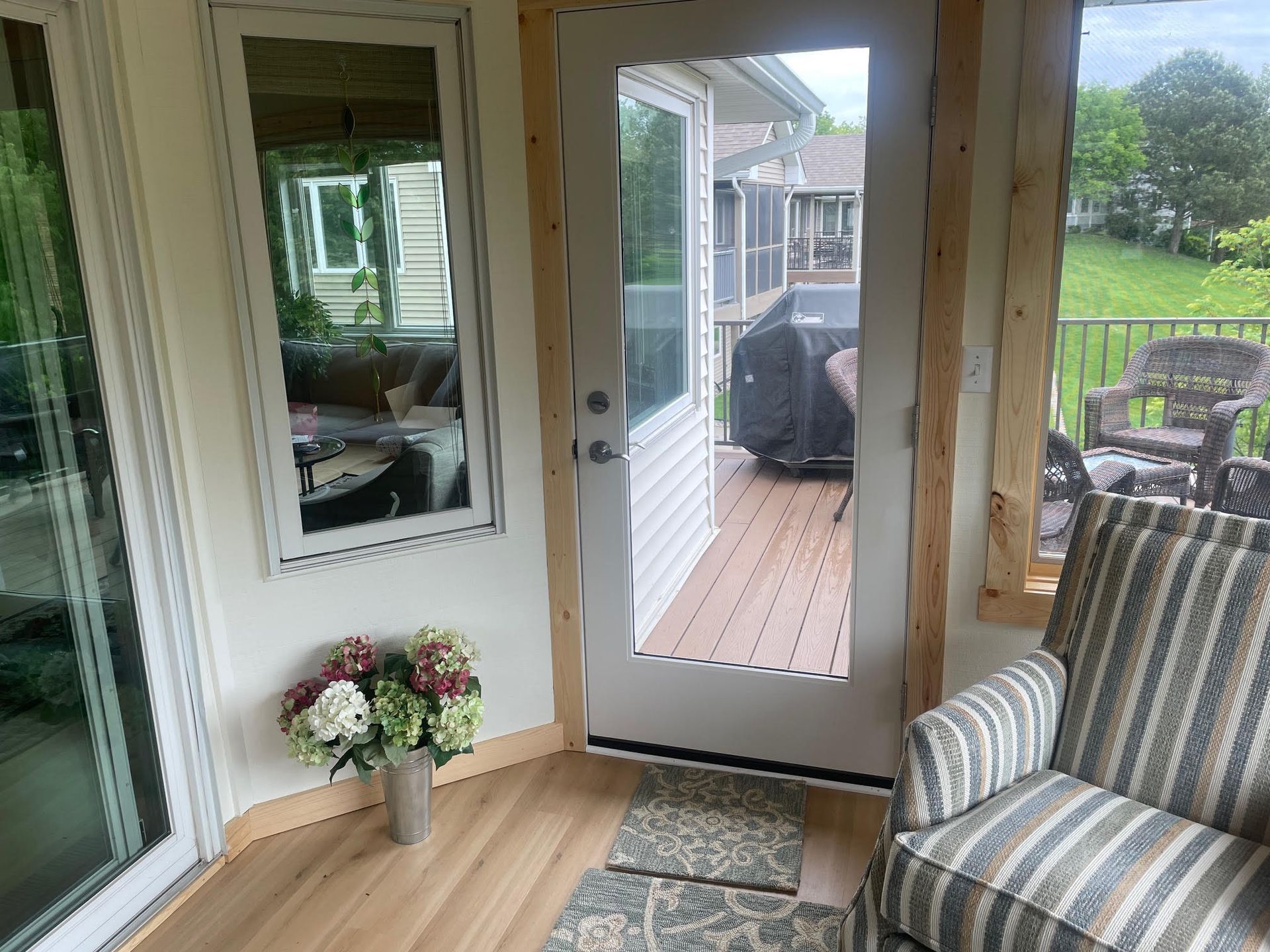 Covered porch with sliding glass door, wicker chair, and open view to a deck and backyard.