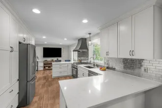 Bright white modern kitchen with stainless steel appliances, island, and wood floors Bright white modern kitchen with stainless steel appliances, island, and wood floors