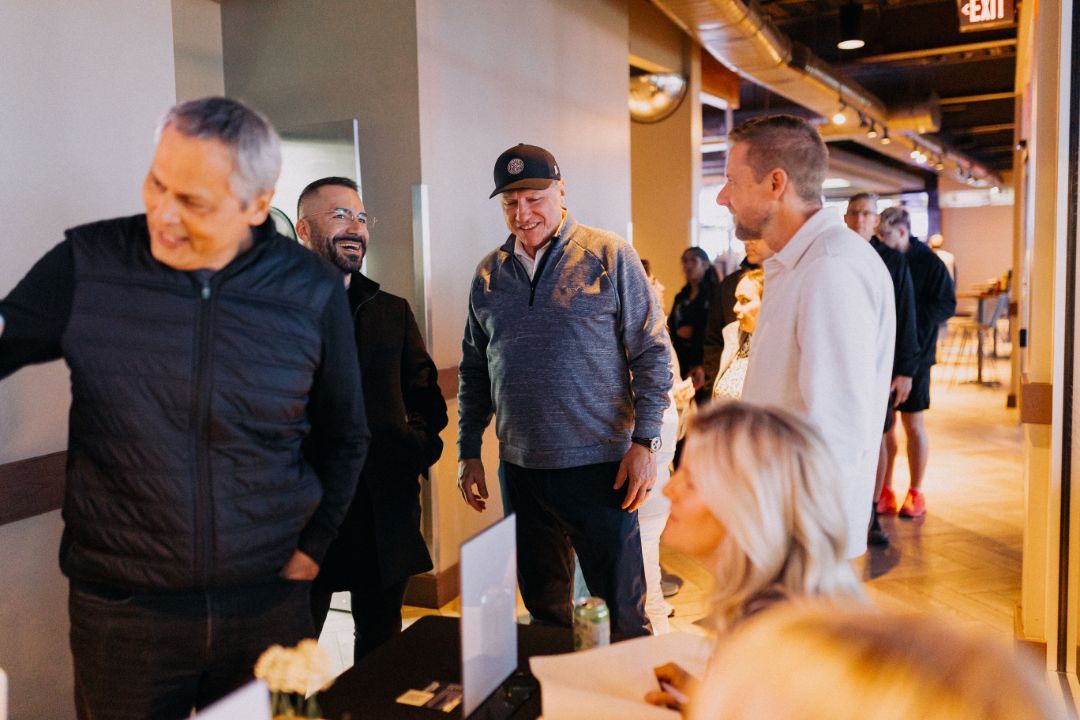 A group of people are standing in a hallway talking to each other.