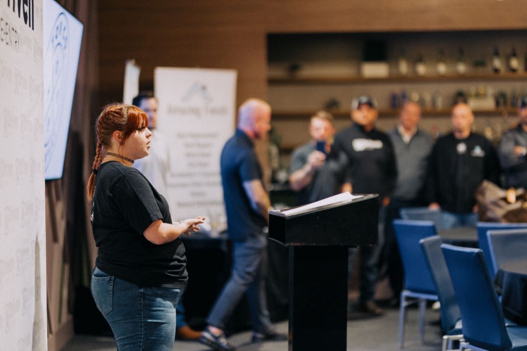 A woman is standing at a podium giving a presentation to a group of people.