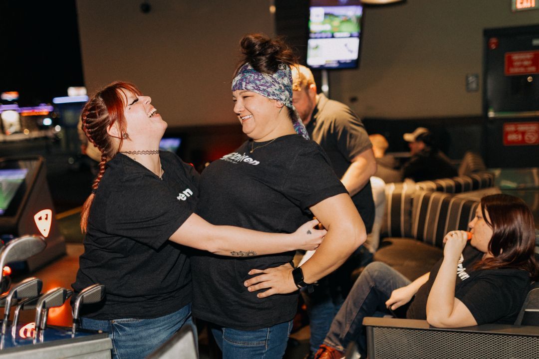 Two women are hugging each other in a bowling alley.