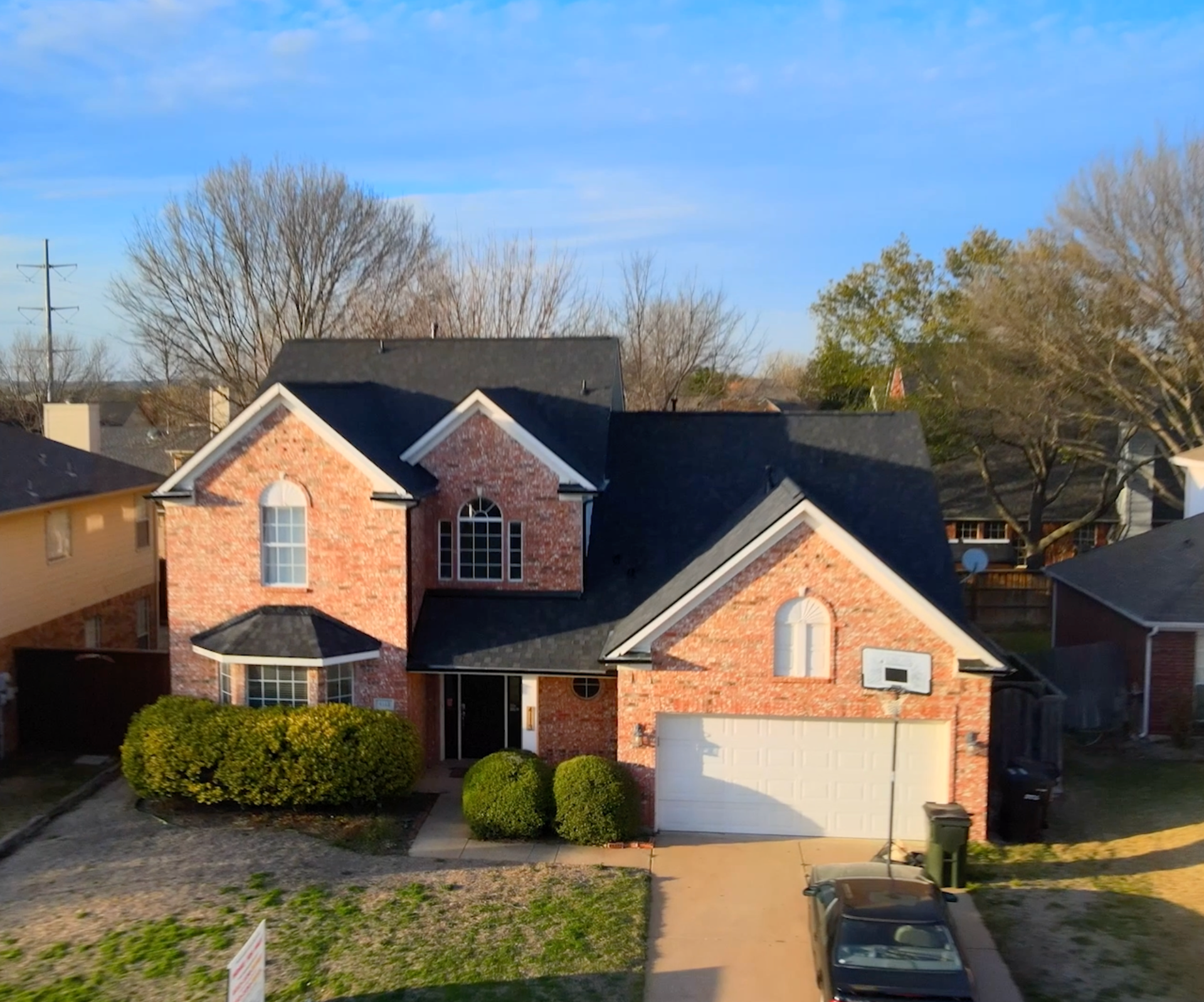An aerial view of a brick house with a black roof