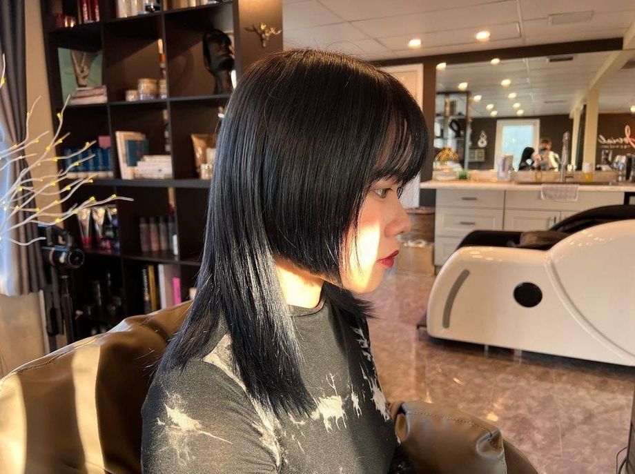 A woman with long black hair is sitting in a chair in a salon.