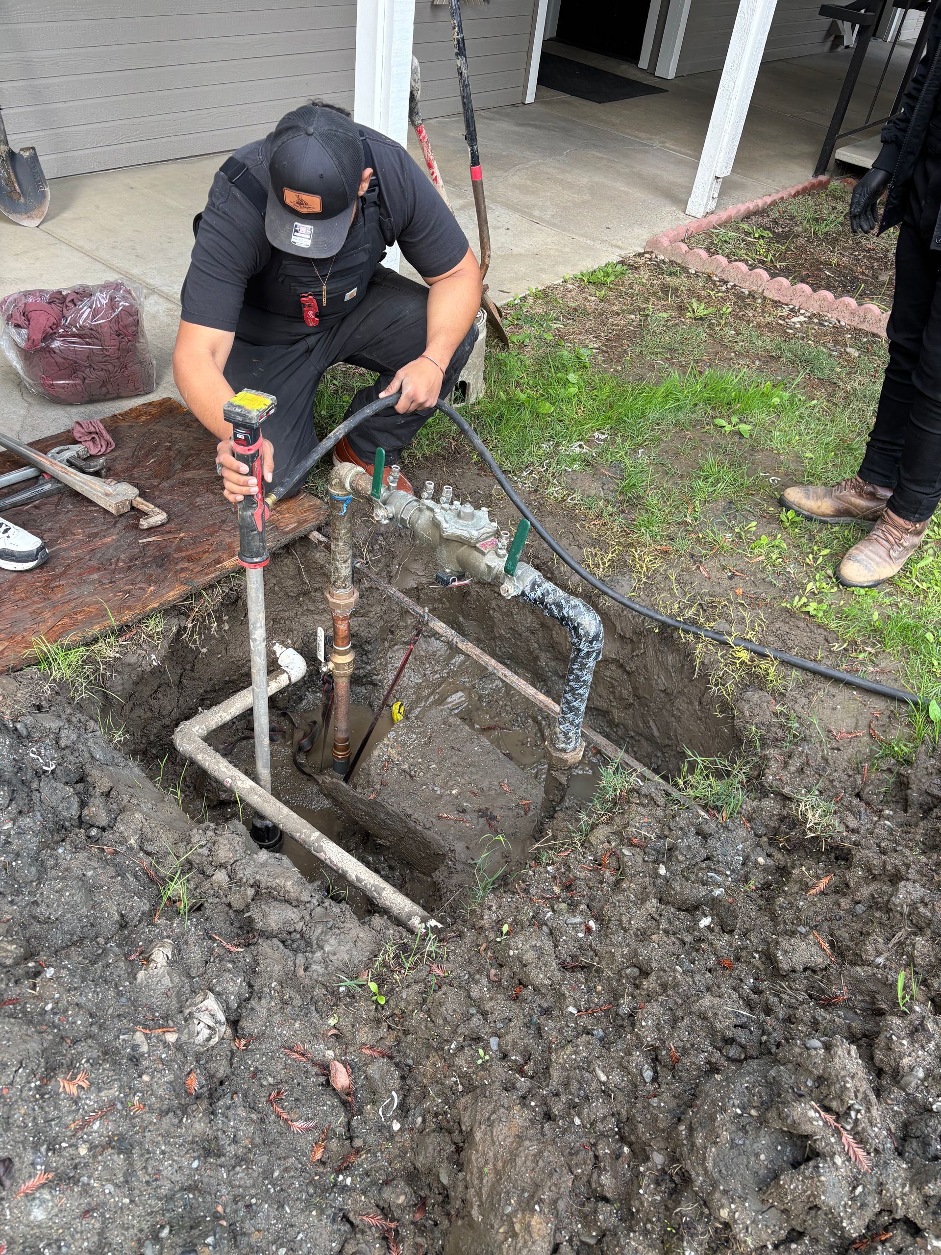 Industrial pipes and ducts in a dim, wet basement or utility room with reflective flooring.