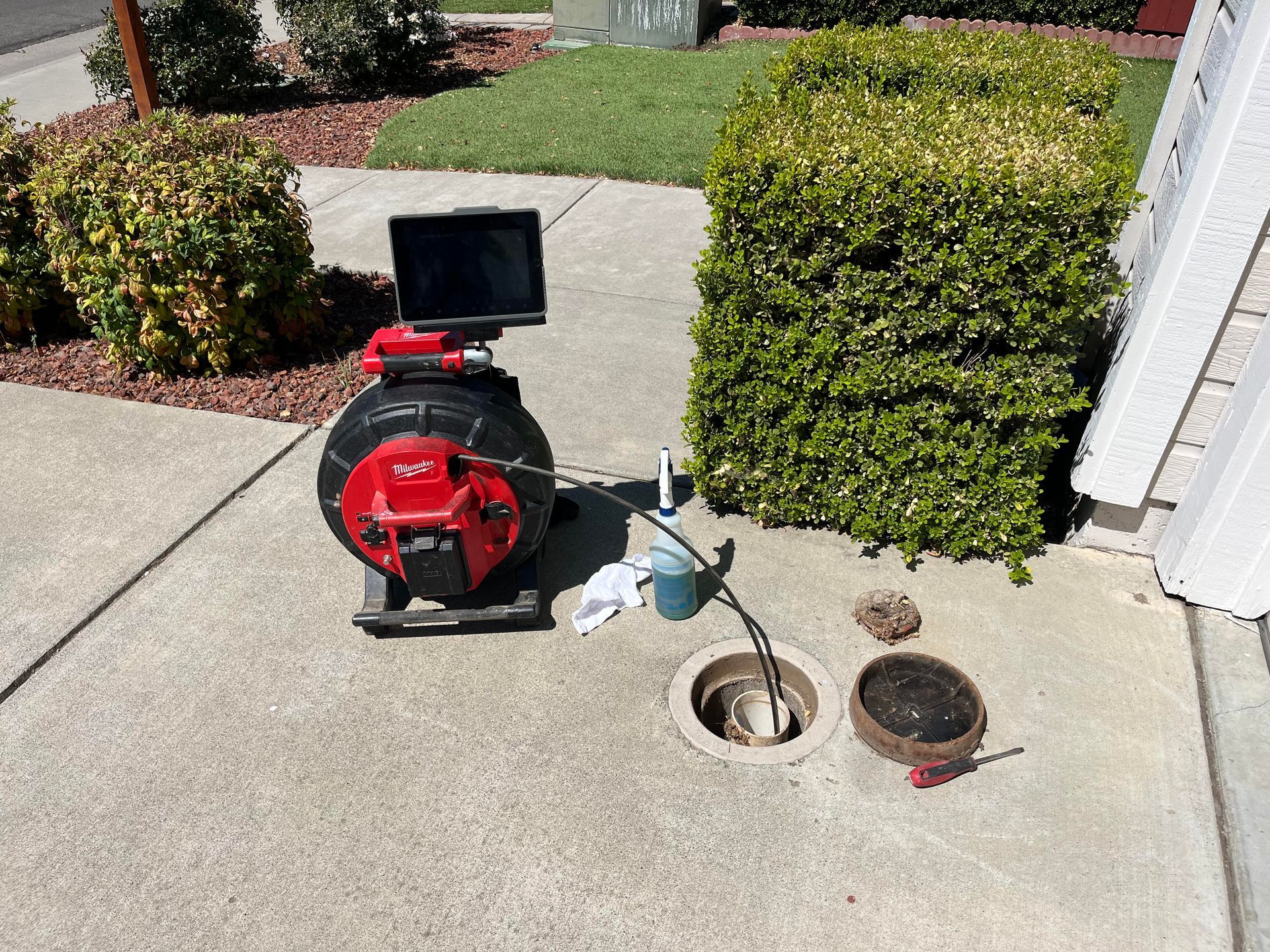 Fire truck hose pumping water into a street drain beside a red fire engine.