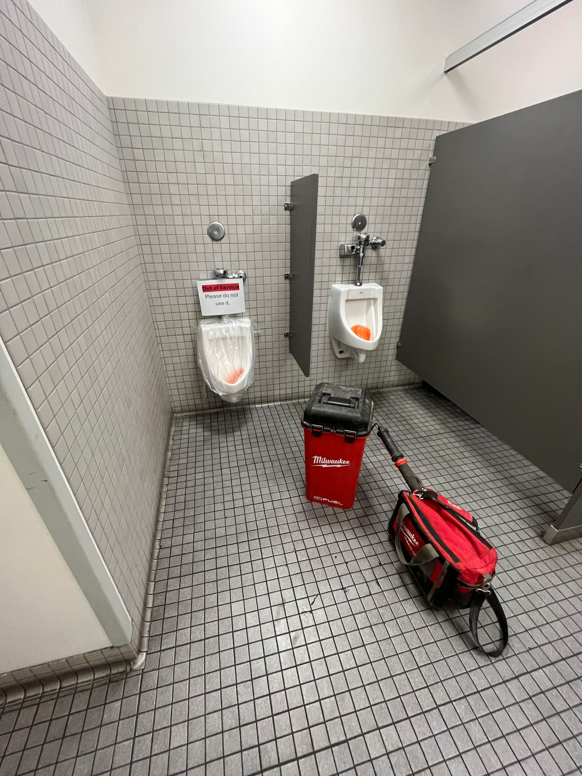 Stainless steel ceiling pipes and ducts in an industrial room with a red valve and lighting fixtures