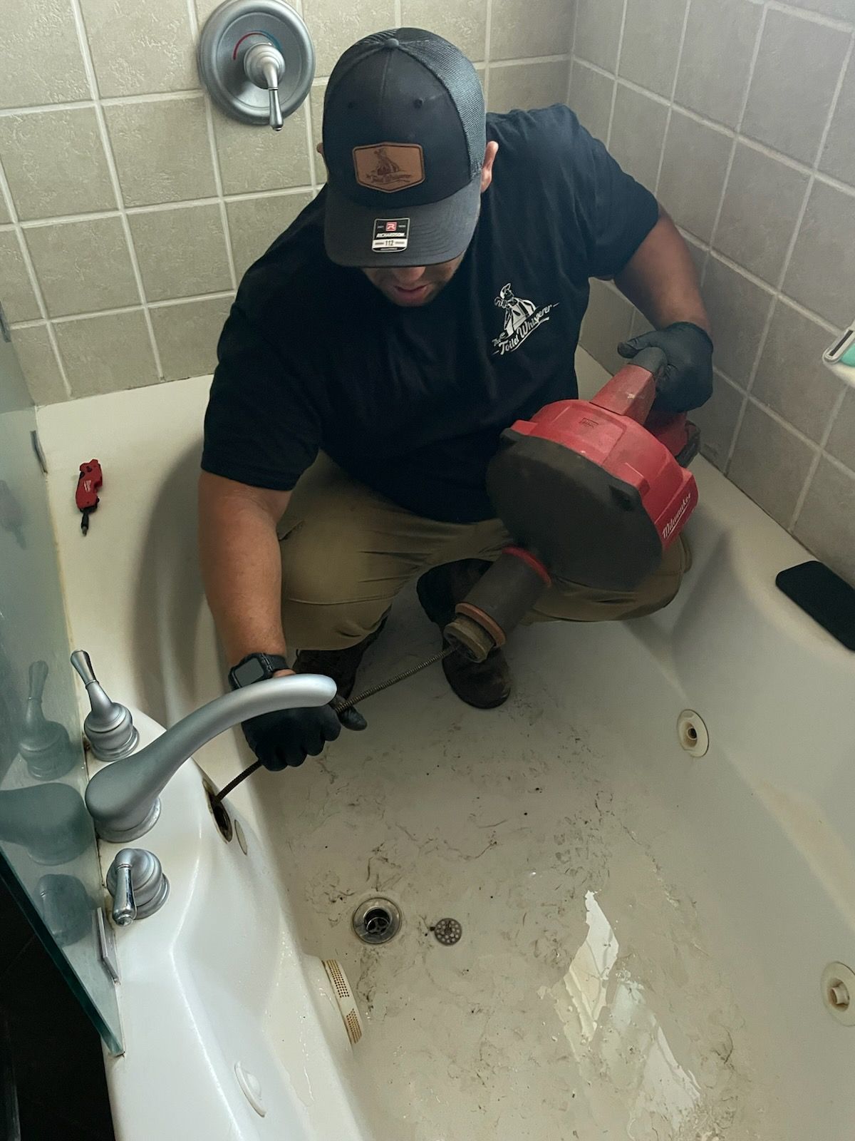 Person using a red plunger to clear a clogged kitchen sink faucet area