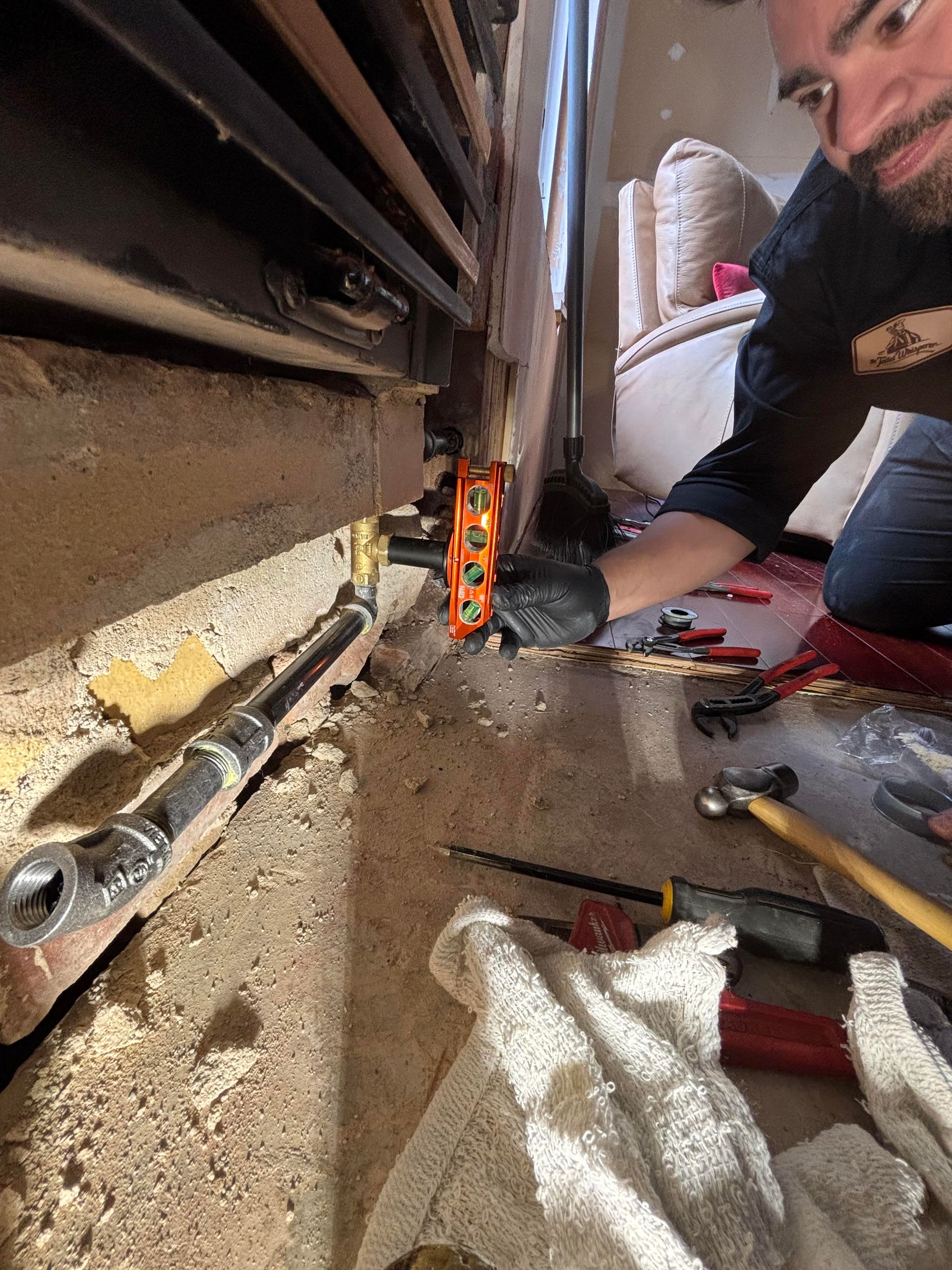 Hands adjusting pipes and valves in a plumbing or heating system, with a wrench in a utility room