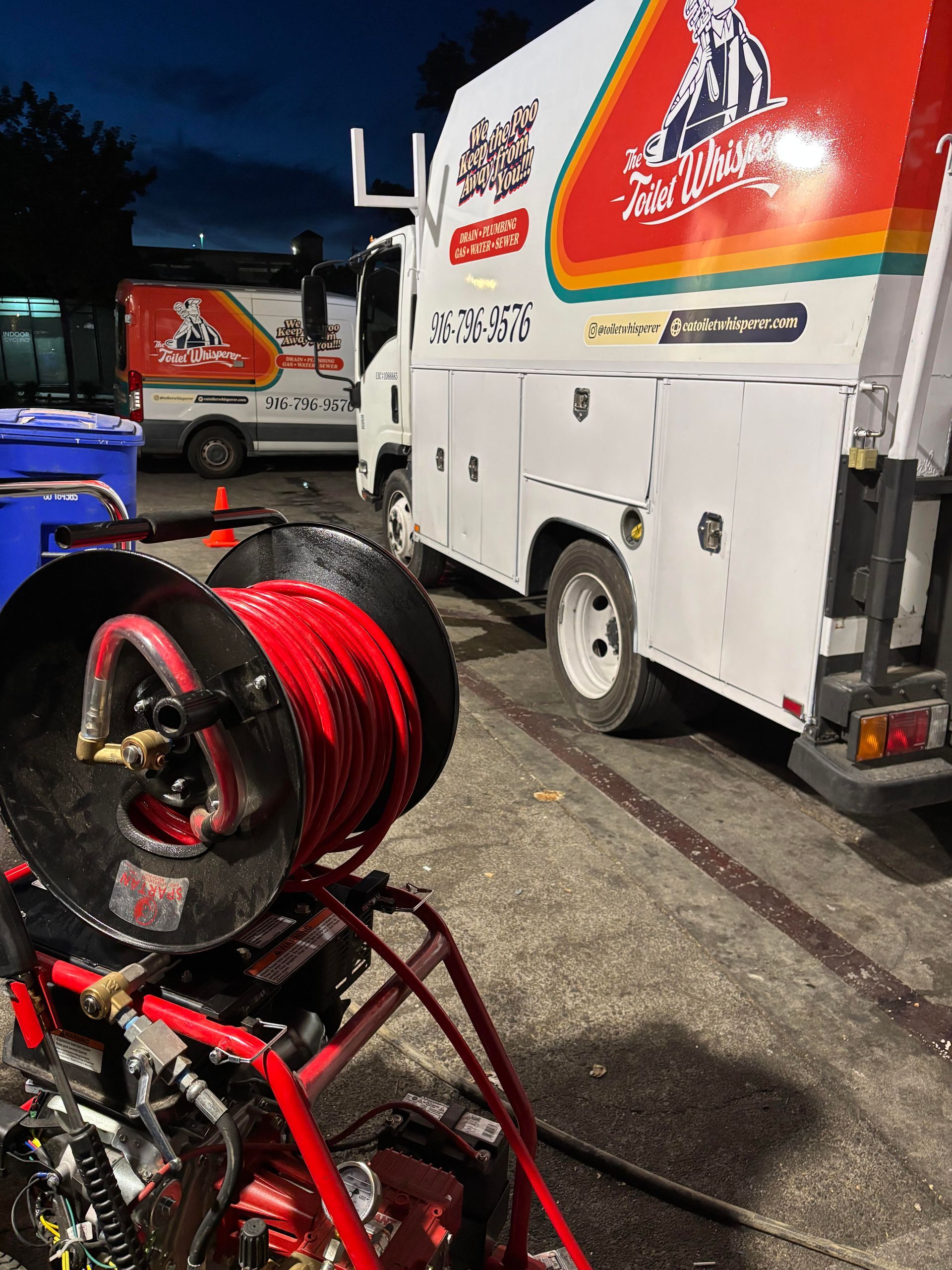 Mechanic leaning over orange machine, inspecting a hose connection in a workshop