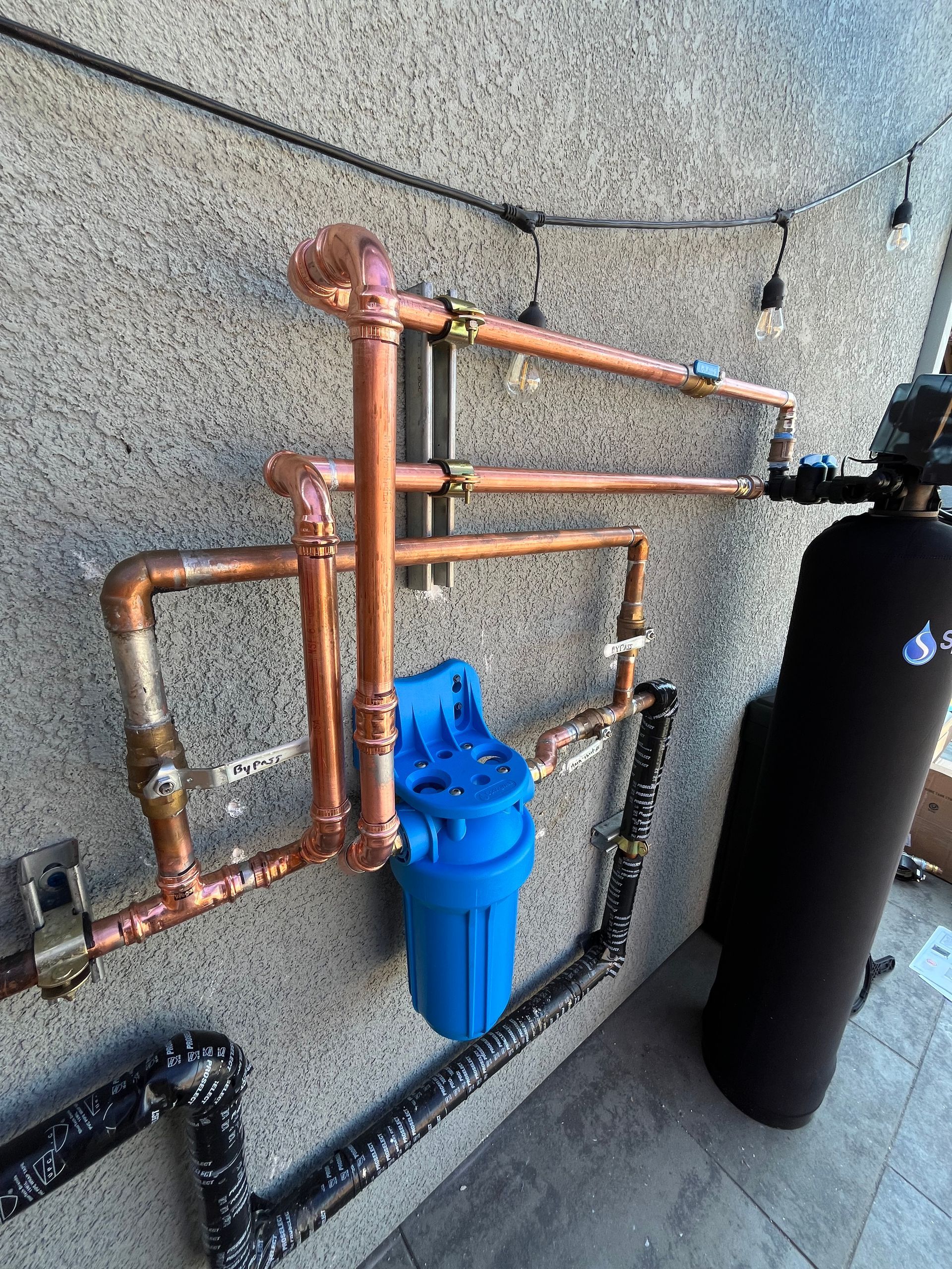 Blue industrial water filtration tanks and pipes in a utility room