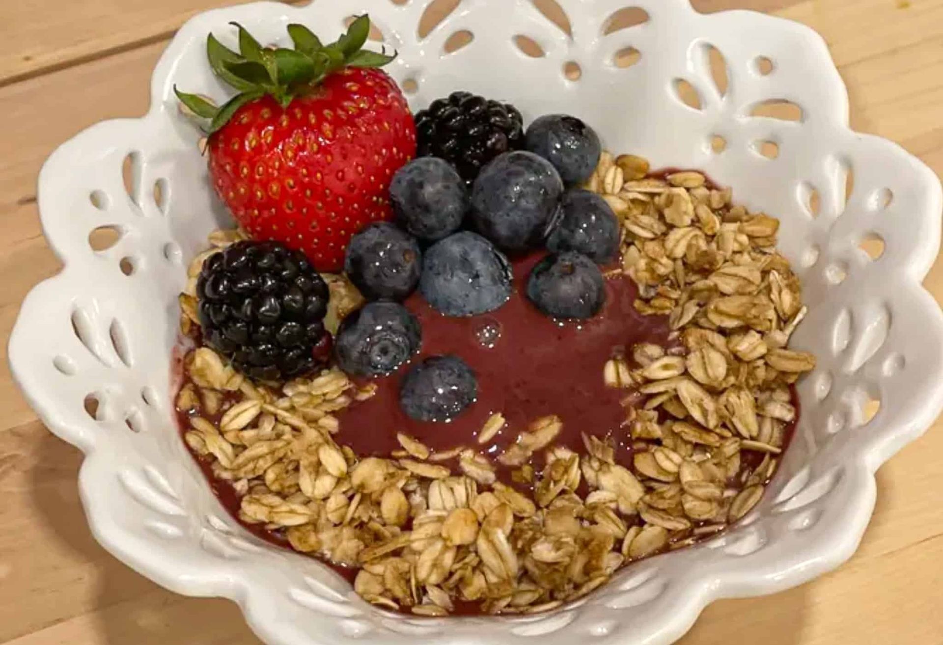 A bowl of oatmeal with berries and a strawberry on top.