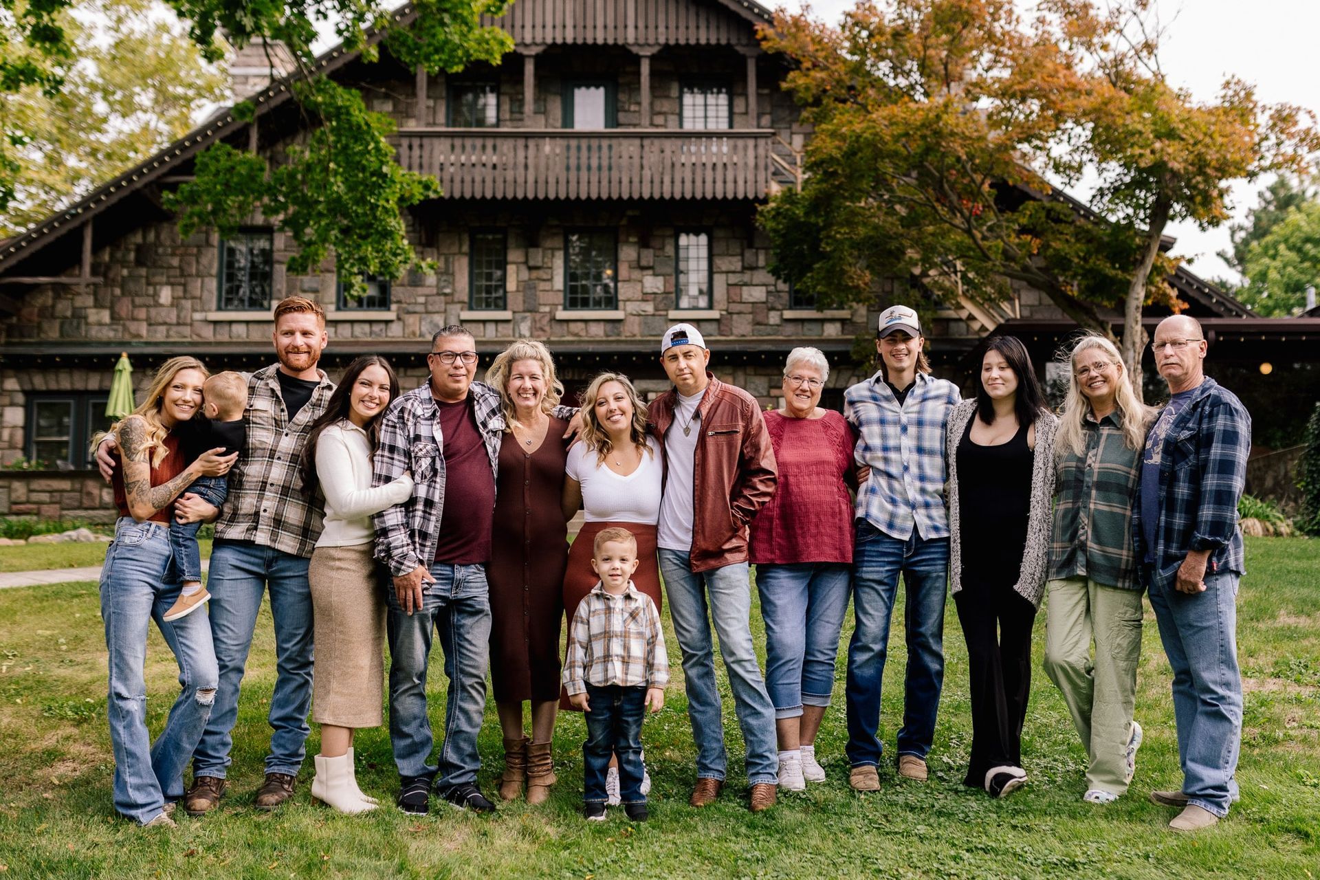 A large family is posing for a picture in front of a large stone house.