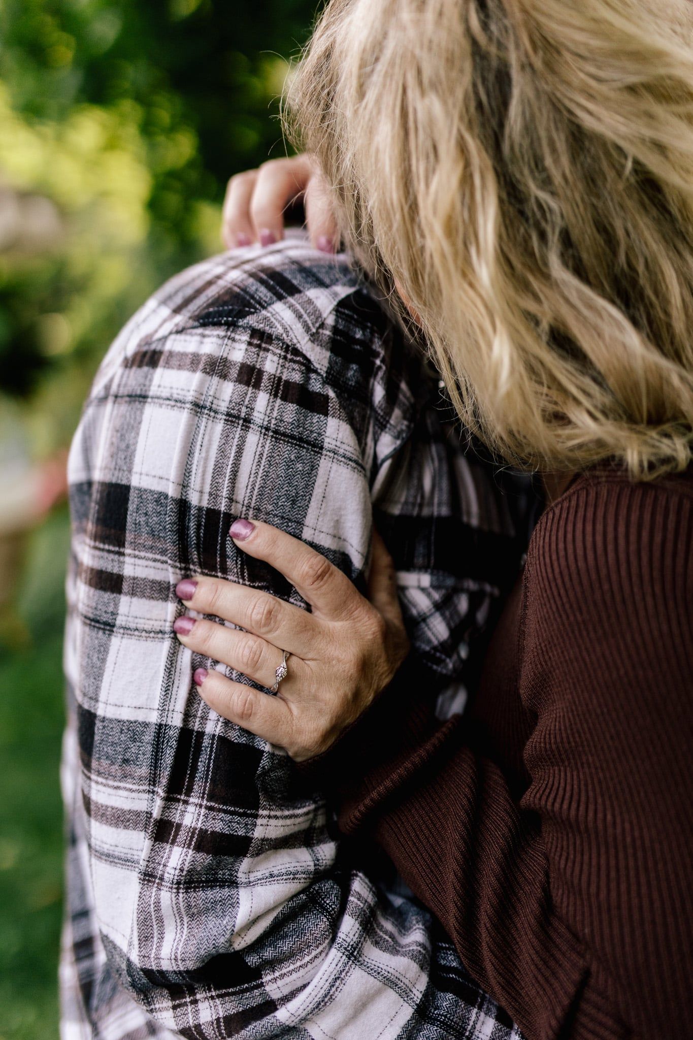 A woman is hugging a man in a plaid shirt.