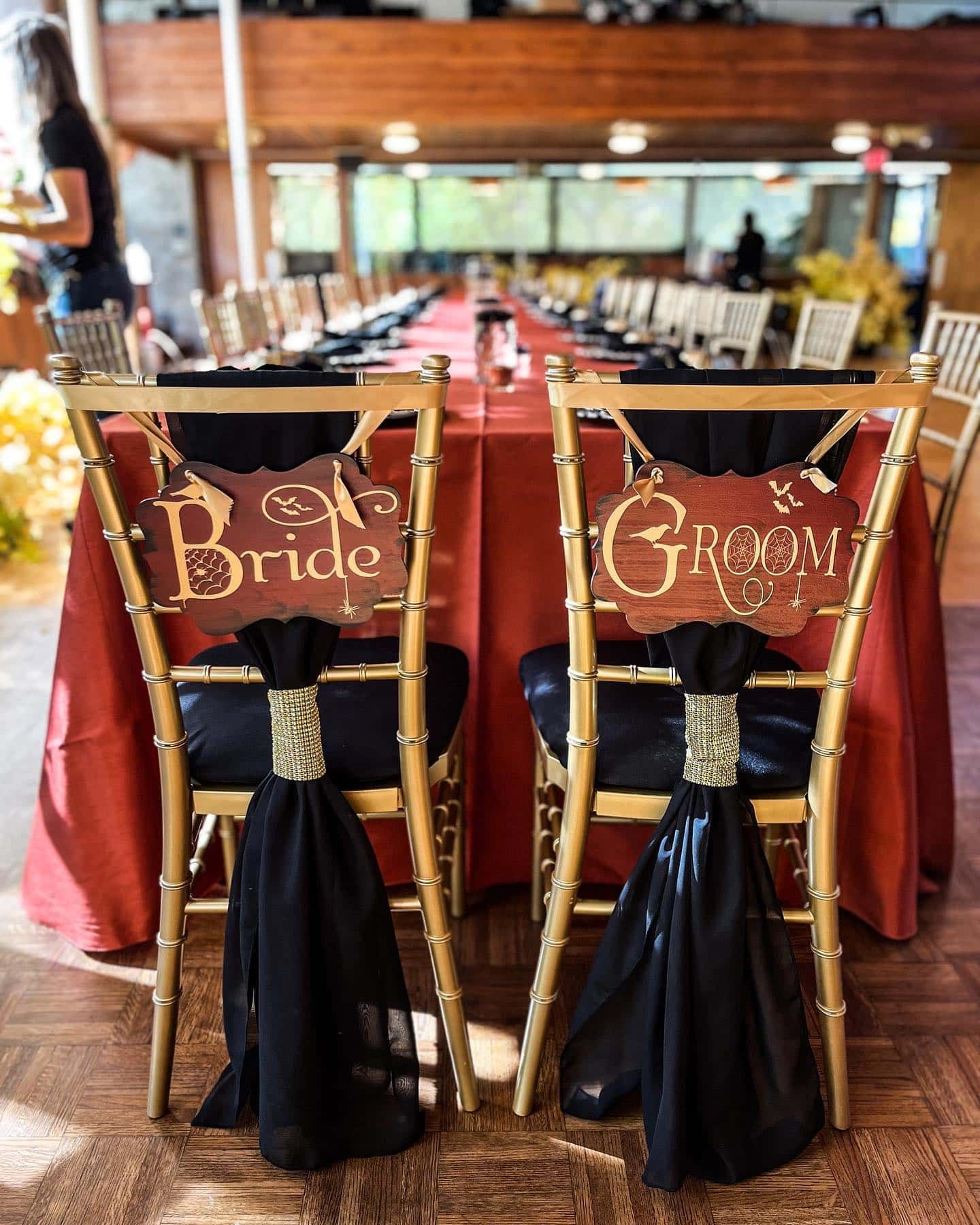 Two chairs with bride and groom signs on them are sitting next to each other at a table.