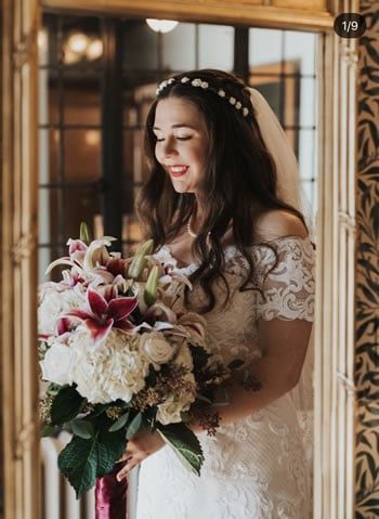 A bride in a wedding dress is holding a bouquet of flowers in front of a mirror.