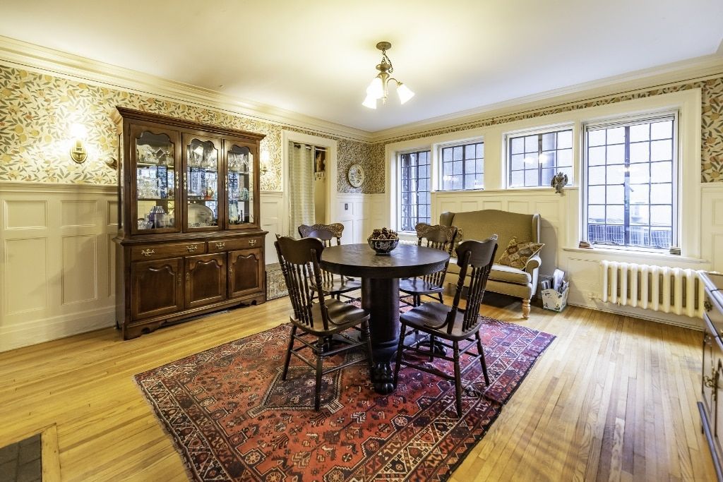 A living room with a table and chairs and a rug on the floor.