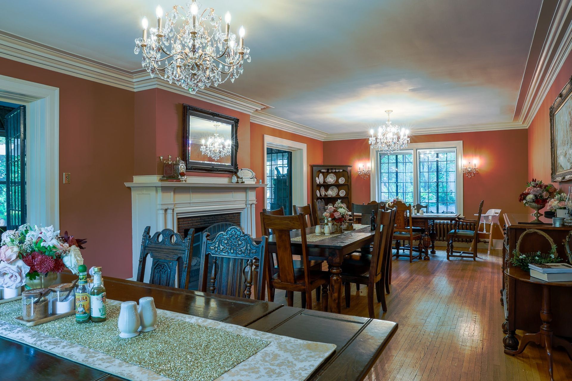 A large dining room with tables , chairs , a fireplace and a chandelier.